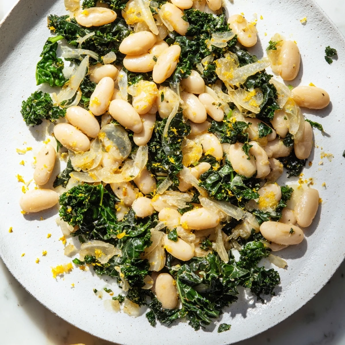 Steaming bowl of Garlicky Beans with Winter Greens, featuring vibrant greens and creamy white beans.