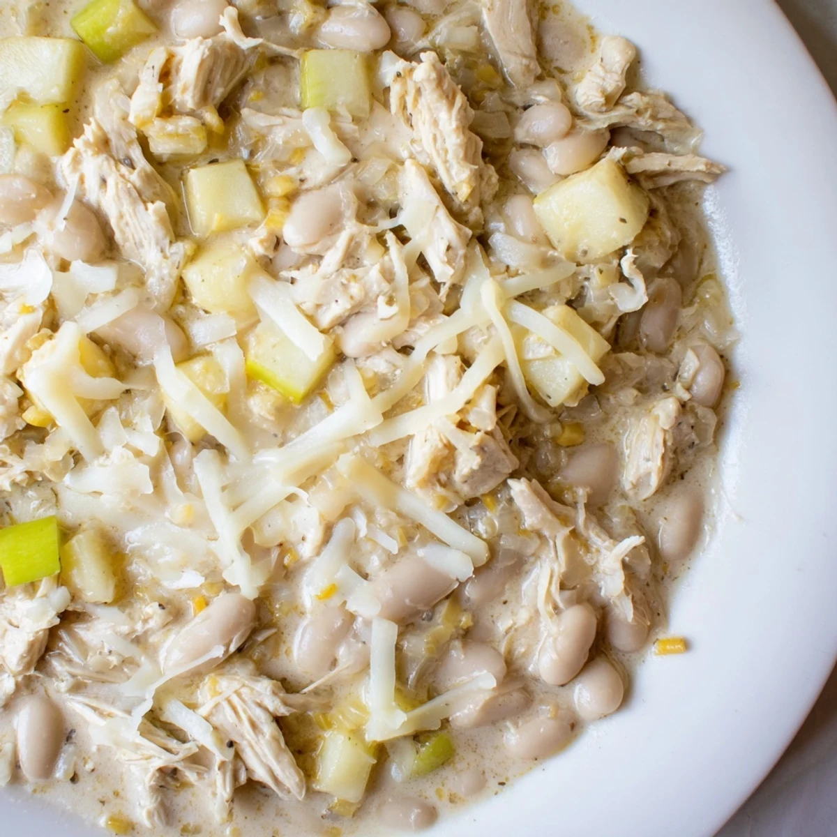 A steaming bowl of 35-Minute White Cheddar Apple Chicken Chili, featuring melted cheese and apples.