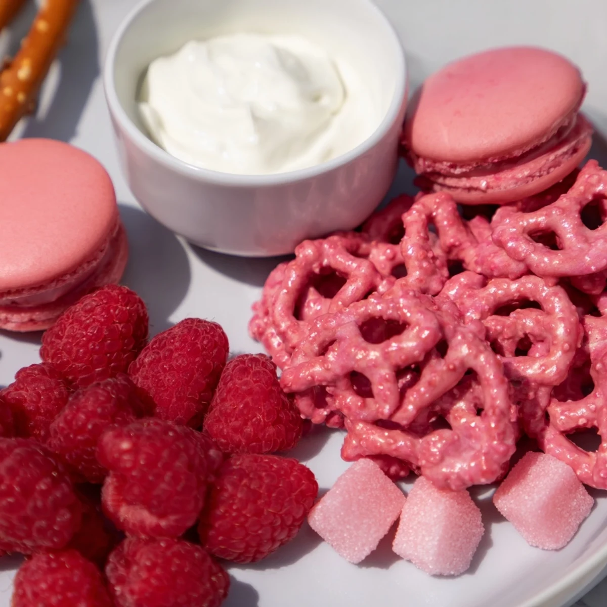Baby reveal snack board overflowing with vibrant pink and blue treats like macarons and pretzels.