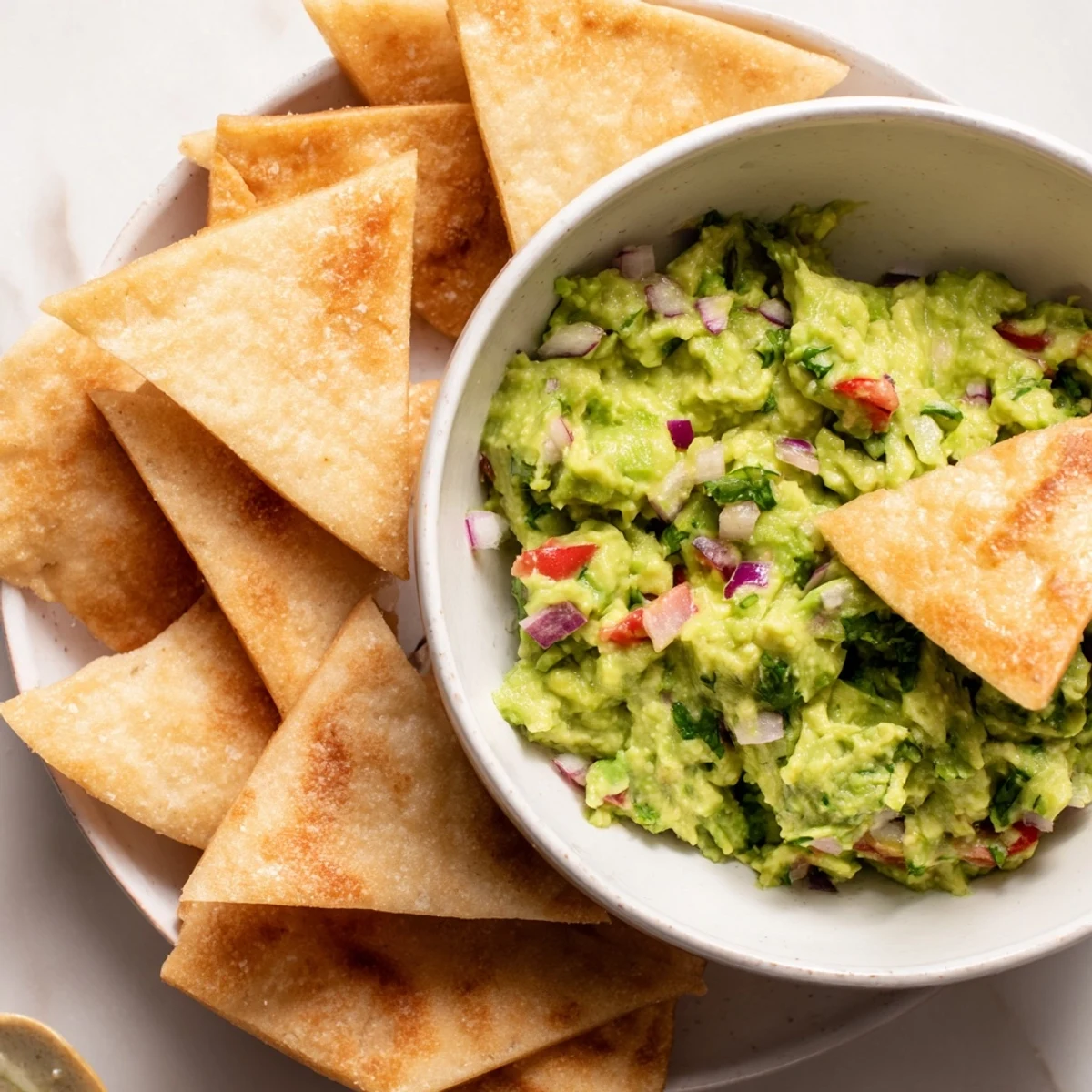 Golden, crispy pita chips surround a vibrant guacamole bowl, a perfect party appetizer.