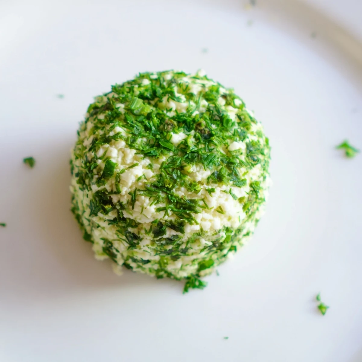 Freshly rolled "Mossy Stone" appetizers, goat cheese covered in green herbs, ready to serve.