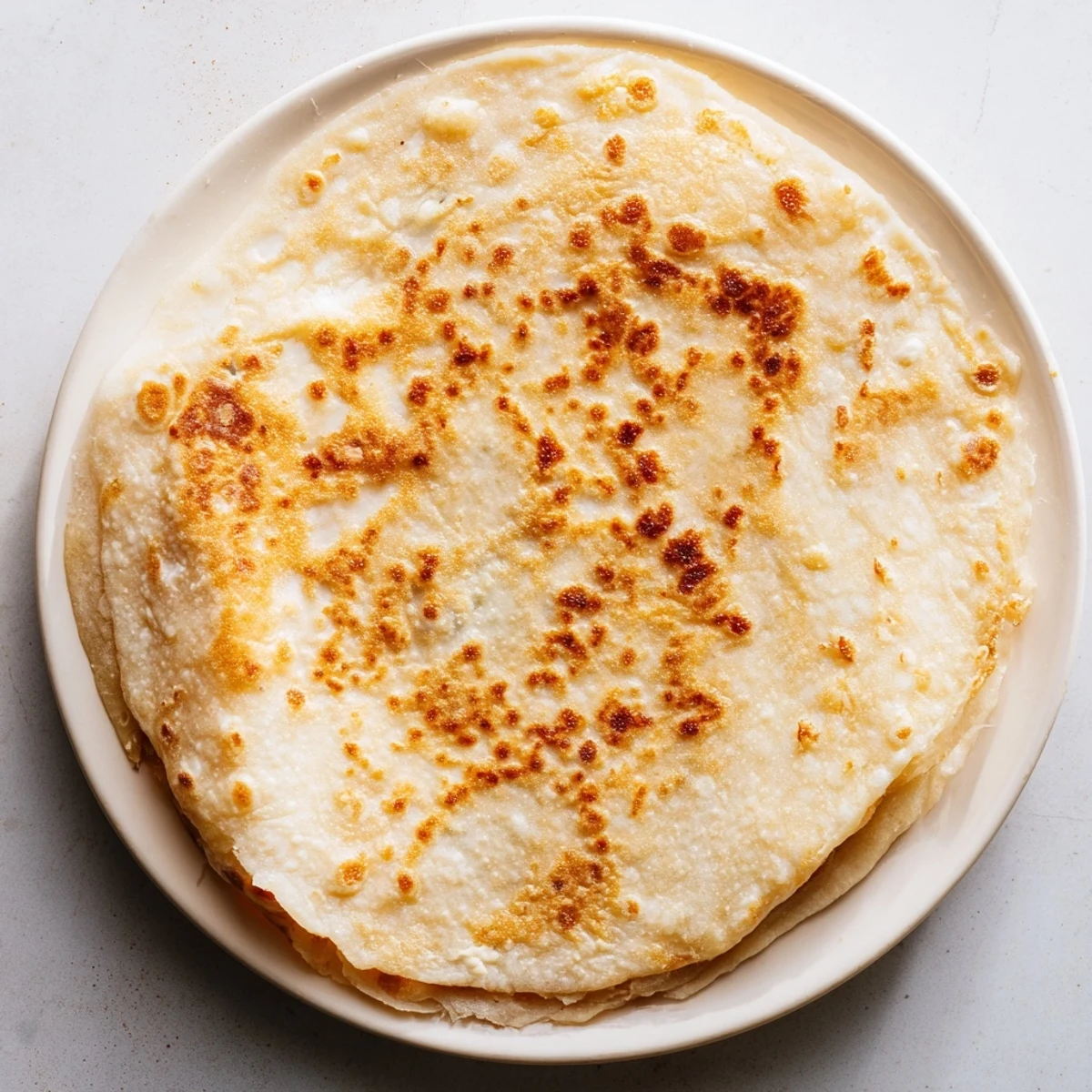 Freshly cooked cottage cheese flatbread, with a soft interior and golden edges, ideal for dipping.