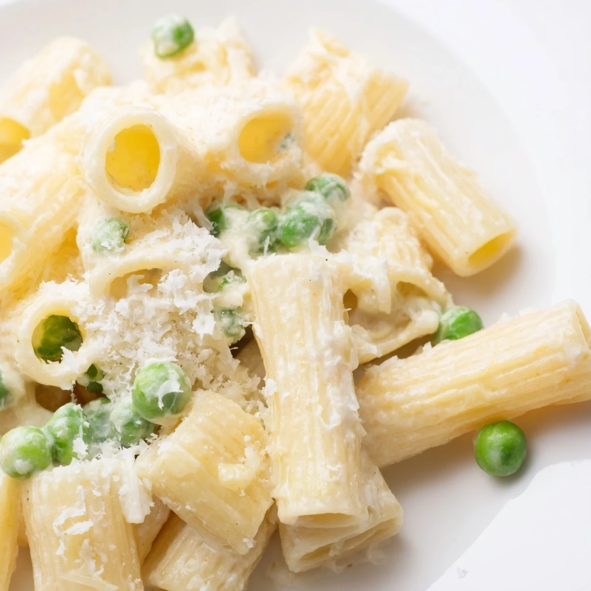 A close-up of Pea & Lemon Ricotta Pasta garnished with fresh basil and extra Parmesan, served warm.