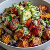 Sweet Potato and Black Bean Bowl with vibrant roasted vegetables, fresh avocado, and a zesty lime dressing drizzle.