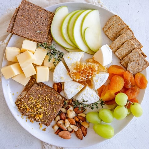 Honeycomb Snack Plate arranged with cheese, fruits, and honey, a pleasing appetizer to share.