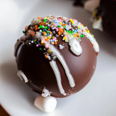 Enjoy a visually appealing, finished Hot Chocolate Bomb with white chocolate drizzle and sprinkles.