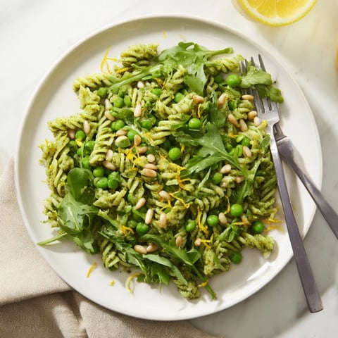 Freshly tossed Spring Green Pesto Pasta Salad with peas, arugula, and pine nuts for a vibrant, cold side dish.