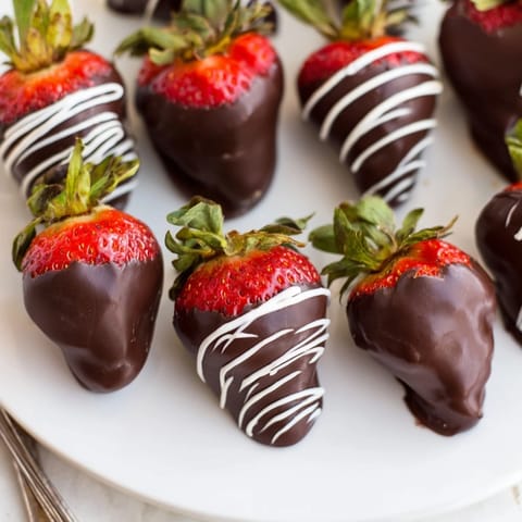 Deep red chocolate covered strawberries with dark chocolate drip; ready for immediate satisfying enjoyment.