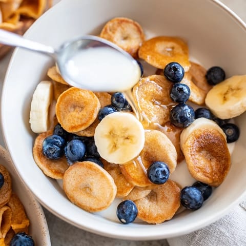 Bite-sized pancake cereal topped with fresh berries and sweet maple syrup for breakfast.  