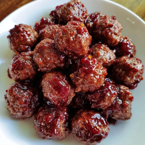 Close-up of juicy cherry-glazed meatballs, coated in a rich, glossy glaze for party food.