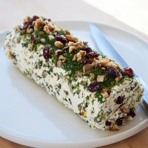 Visually stunning Winter Snowdrift Goat Cheese Log, showcasing herbs, nuts, and cranberries ready to enjoy.