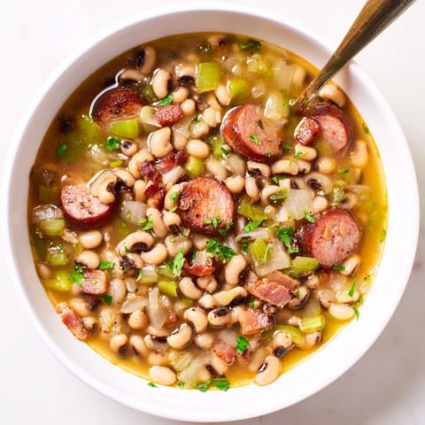 Hearty Southern-Style Black-Eyed Peas topped with fresh parsley and a dash of hot sauce, served alongside cornbread.