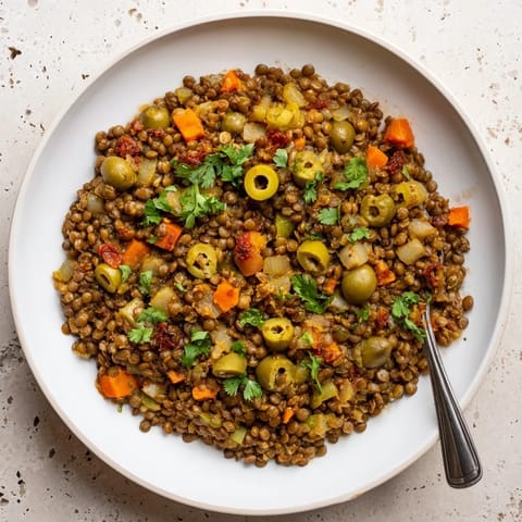A spoonful of vibrant Cuban-Inspired Lentil Picadillo beside fluffy rice, garnished with fresh cilantro and briny olives.