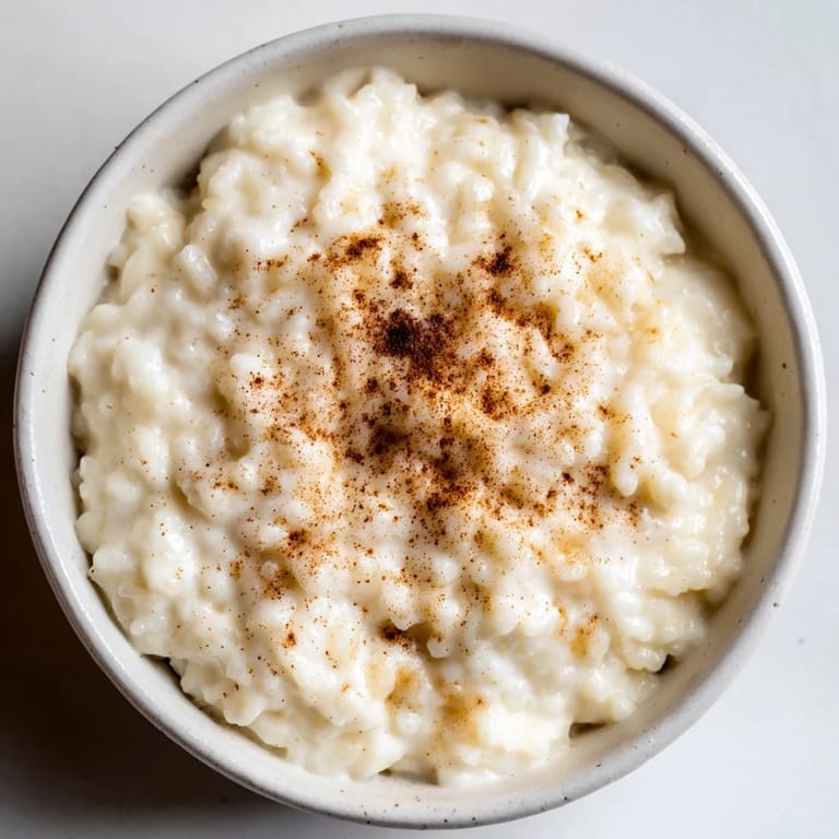 Enjoy a warm bowl of rice pudding made from leftover rice, sprinkled with cinnamon for serving.