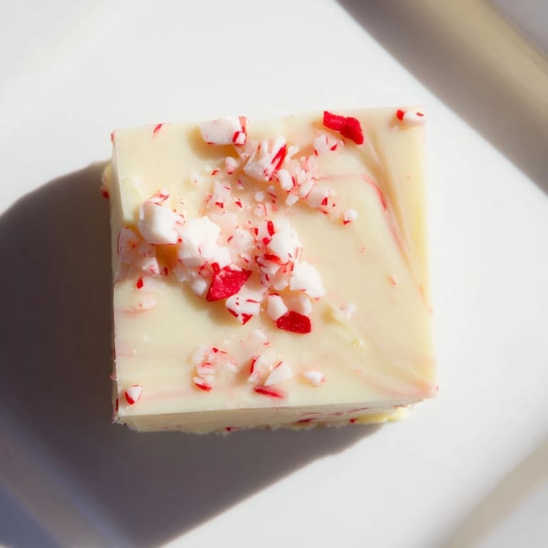 Irresistible square of White Chocolate Peppermint Bark Fudge with crushed candy canes, ready to enjoy.