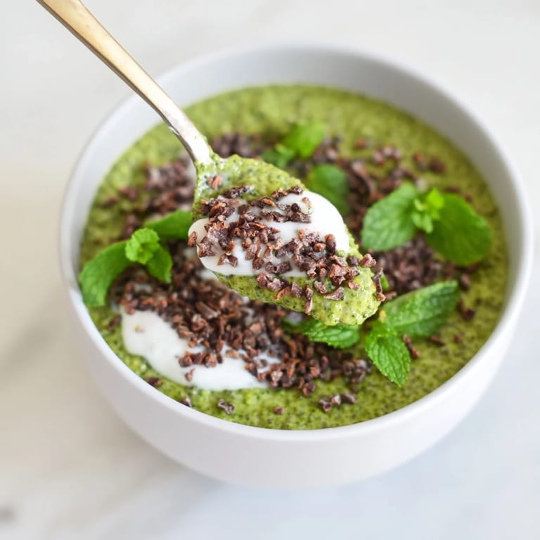 A vibrant breakfast bowl of Grinch Green Mint Matcha Chia Pudding, boasting fresh mint and berries, visually appealing.